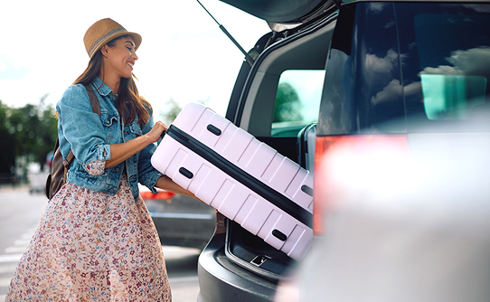 Woman loading car with suitcase